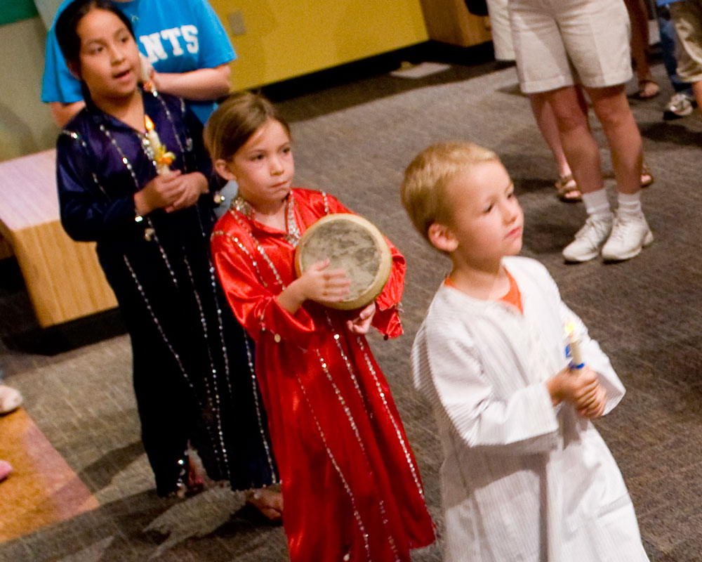 Child playing small drum in Take Me There: Egypt exhibit.